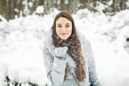 年轻女子冬季画像。冬天妇女在森林里吹雪