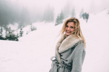 年轻漂亮的女孩等待她的情人在山的中间覆盖着积雪