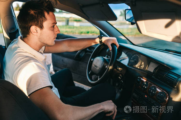 年轻迷人的白种人穿着白色t恤坐在车里