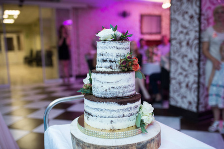 乡村风格的婚礼蛋糕。 三层巧克力婚礼饼干蛋糕装饰白色和橙色的花。 婚礼蛋糕