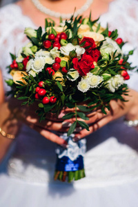 婚礼花束与红色玫瑰和白色雏菊在新娘的手里