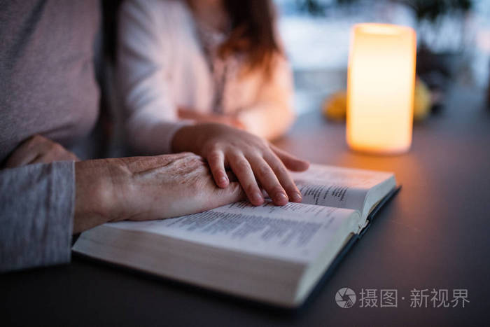 一个小女孩和祖母在家里读圣经