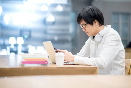 在图书馆使用智能手机的年轻亚裔男子大学生