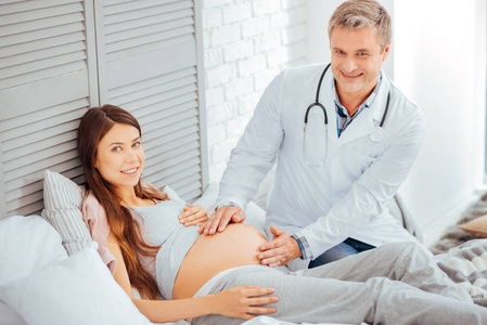 怀孕的年轻妇女和儿科医生微笑入照相机