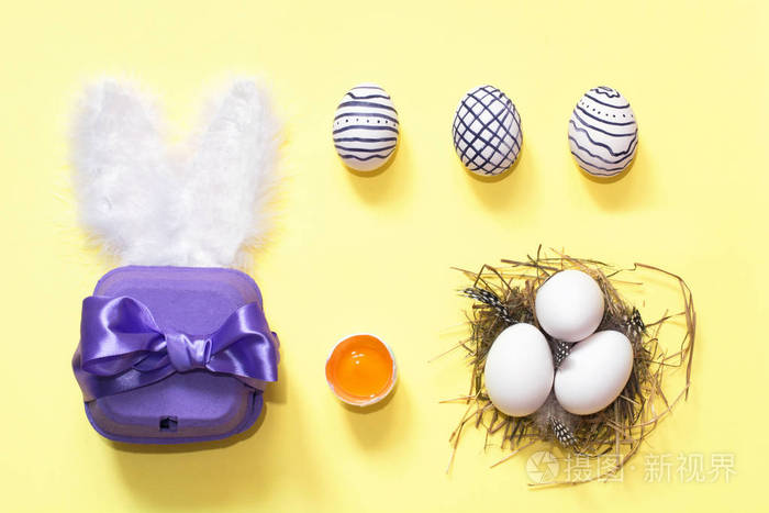 创造性的复活节作文与绘的蛋, 紫罗兰色盒和巢, 在黄色背景。平躺