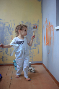 小男孩玩油漆刷帮助翻新墙壁的彩色油漆