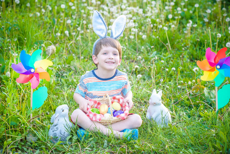 在复活节寻找复活节彩蛋在春天的花园里的小男孩。与传统的兔子庆祝盛宴可爱小孩