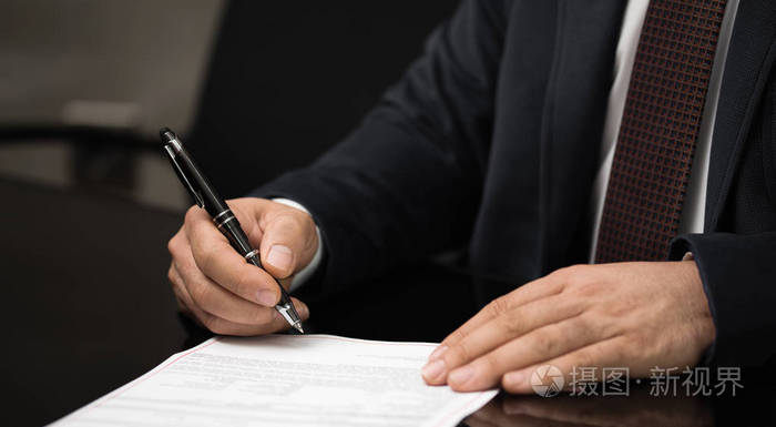 用 nibbed 钢笔在一张白纸上签名或写文件的商人的手