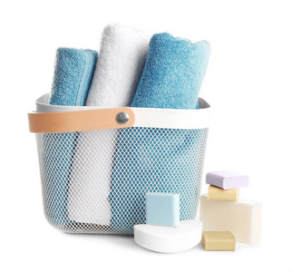 白色背景的软毛巾和不同肥皂条的篮子