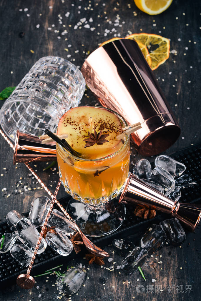 热的酒精鸡尾酒和苹果一起喝在黑色的木制背景上