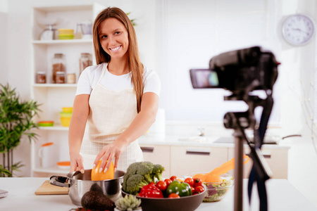 美丽的年轻女子拍摄她的博客广播健康食品在家里。