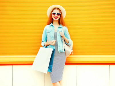 时尚微笑的妇女与购物袋, 草帽在橙色 ba