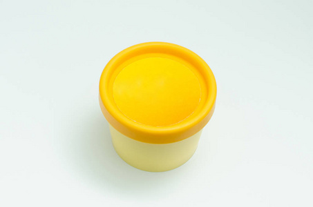 白色背景上分离的黄色奶油罐。 护肤品包装。 不透明的美容霜容器。 标志的位置