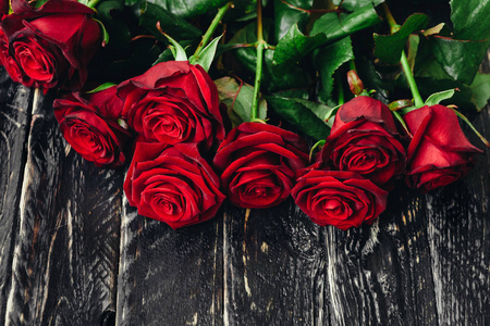 黑色木制背景上美丽的红玫瑰