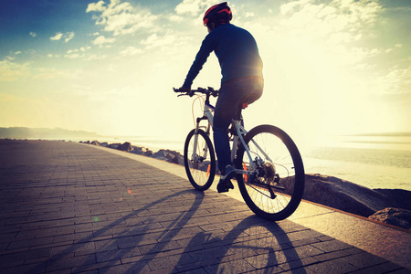 骑自行车的人骑自行车在日出的海岸小路上