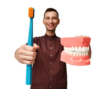大牙齿假人和牙医医生用牙刷显示如何正确刷牙
