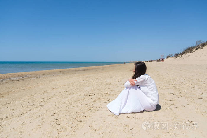 坐在海边的年轻女子看着远处