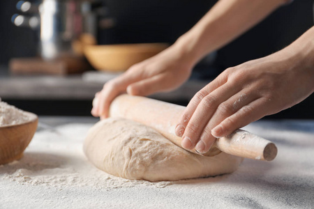 擀面团的人在桌子上撒上面粉那个年轻女人擀生面团用擀面杖女人用