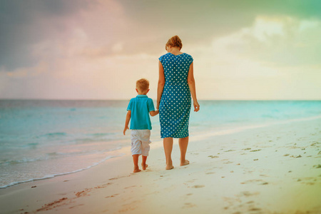 母亲和儿子在日落海滩上行走