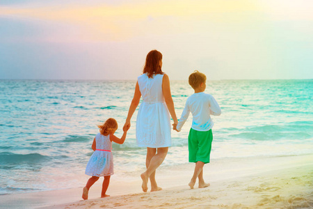 母亲和两个孩子在沙滩上行走