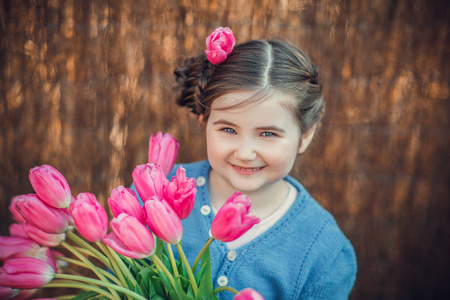 小女孩高兴地笑着拿着大郁金香花束。 阳光明媚的春天户外。