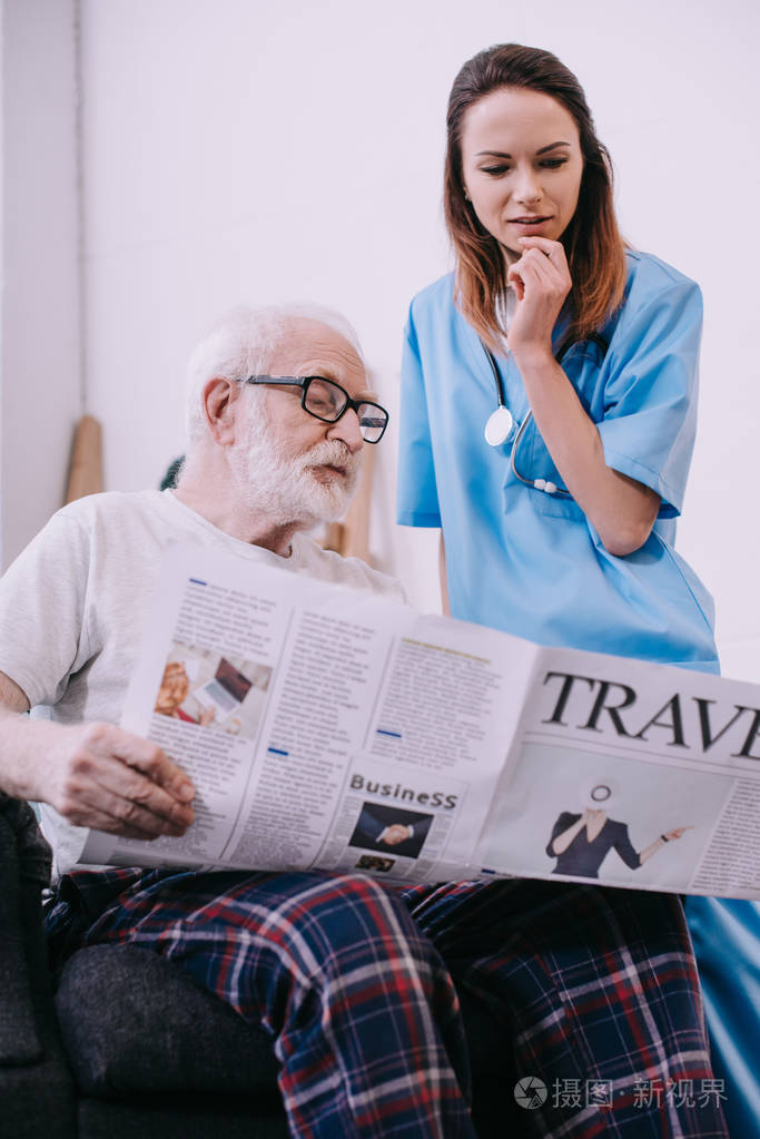 护士站在老人面前看报纸