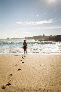 女人穿过一个孤独美丽的海滩的沙滩