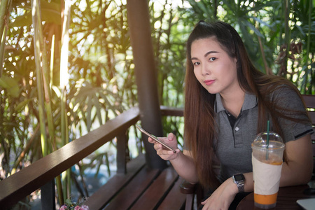 美丽的女人手持手机, 看着相机