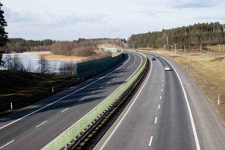 雨天秋日落叶双车道公路行驶空置沥青路与隧道, 绿地和现代城市天际线