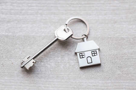 房子钥匙和钥匙串以房子的形式在木板。不动产抵押搬家或租赁财产的概念