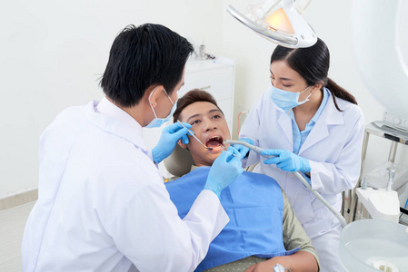 牙科医生和护士在检查病人牙齿时使用口镜吸管和牙科医生