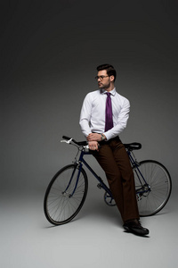 时尚商人坐在灰色自行车上的形象