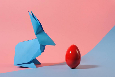 折纸彩色兔子与鸡蛋在两个色调的背景。 复活节的想法。