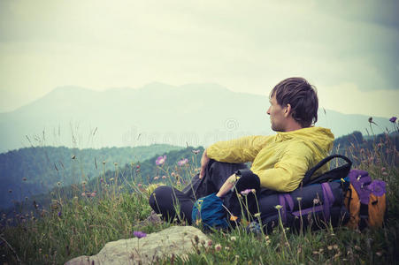 背负背包的男旅行者，在山的背景下放松