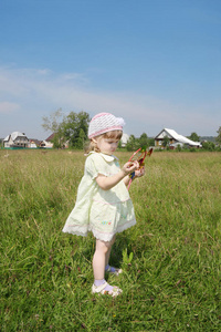 可爱的小女孩看着绿草地上的风车