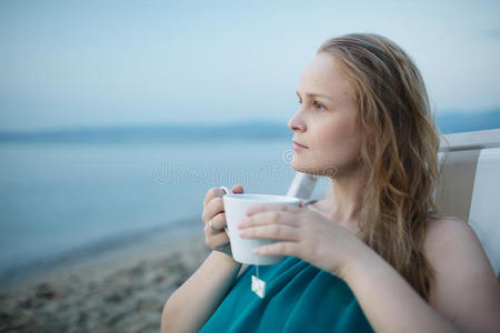 在海边喝茶的女人