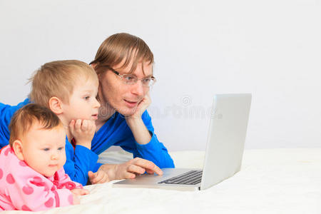 爸爸带着孩子在家看笔记本电脑