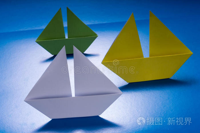 在蓝色纸海上航行的纸船折纸船