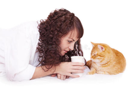 一个女孩拿着一杯咖啡和她的猫在床上