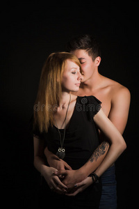 健美男长一对美丽的年轻夫妇在黑色背景下拥抱亲吻.照片