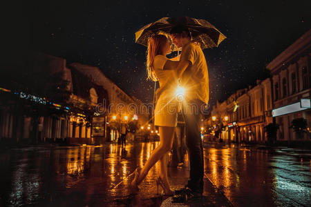 雨中的爱雨伞下亲吻情侣的剪影