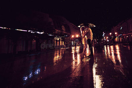 雨中的爱雨伞下亲吻情侣的剪影