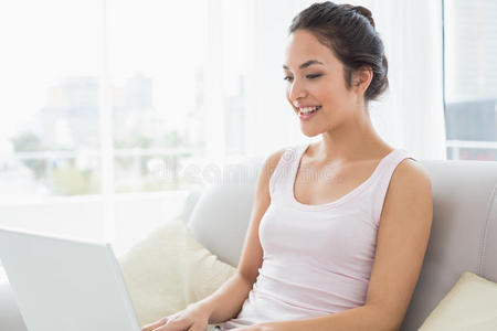 女青年在客厅沙发上使用笔记本电脑