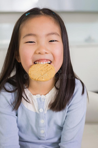 一个微笑的小女孩正在吃饼干的画像