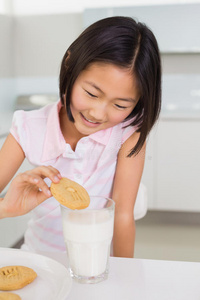 微笑的女孩在家吃饼干和牛奶