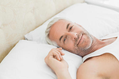 一个微笑的成熟男人躺在床上的特写镜头