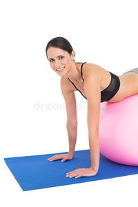 一位健康的年轻女子在健身球上伸展的画像