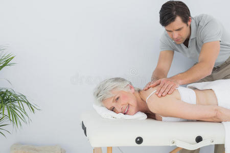 男性理疗师给一位老年妇女按摩背部