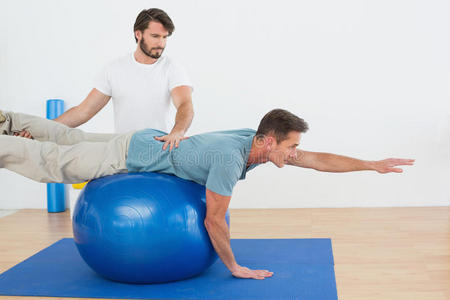 物理治疗师帮助年轻人练习瑜伽球