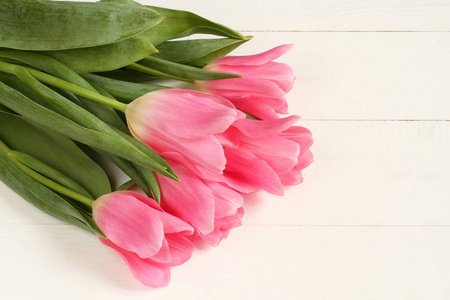 五朵粉红色的郁金香花在白色的木制桌子上